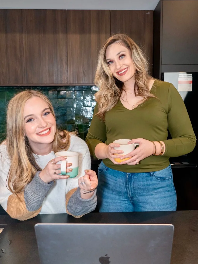 The two founders of The PathBuilders, coffee in hand, at a kitchen island with a laptop.