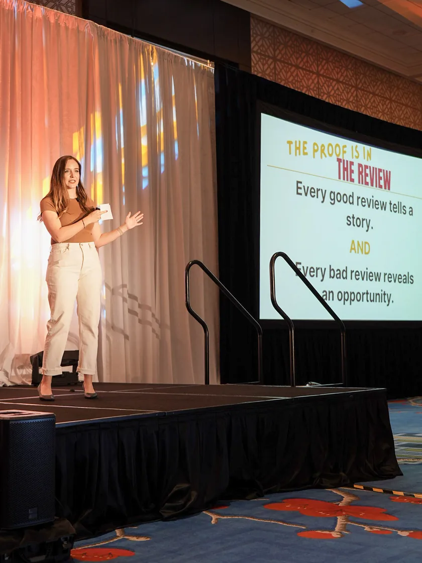 A PathBuilders founder speaking on stage beside a slide reading The Proof Is In The Review.